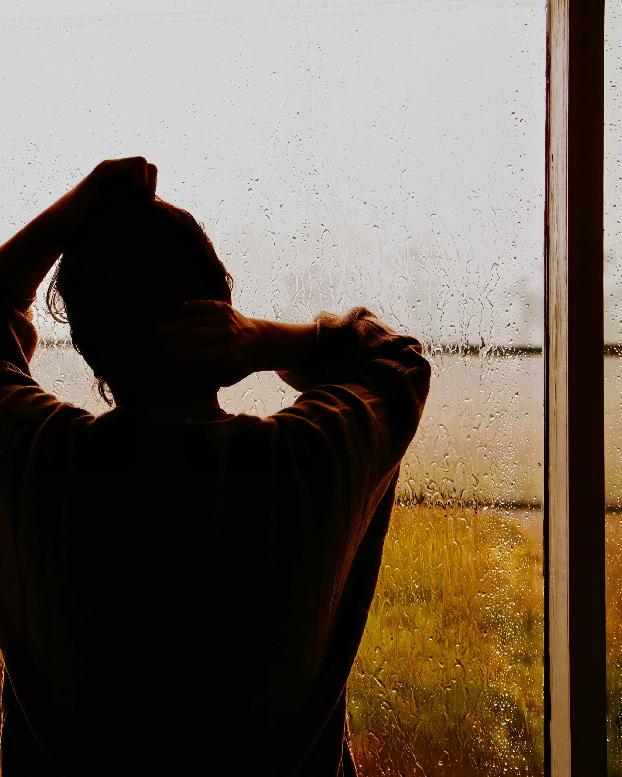 long distance parent looking out rainy window struggling with isolation and distance