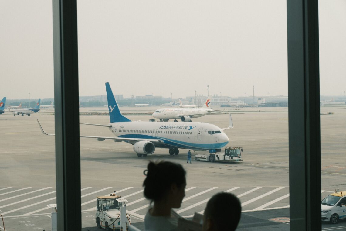 Parent and child saying goodbye at the airport as the airplane taxis to the departure gate